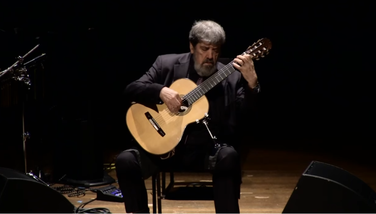 Oscar Ghiglia beim Gitarrespiel auf einer dunklen Bühne